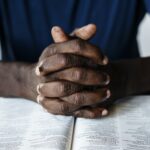 African American male hands resting on an open bible